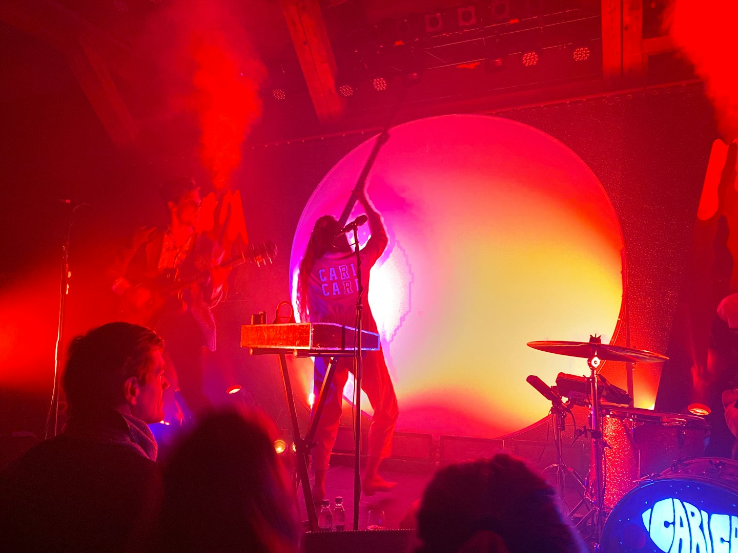 Hudobníci hrajú energický koncert na zadymenom pódiu.